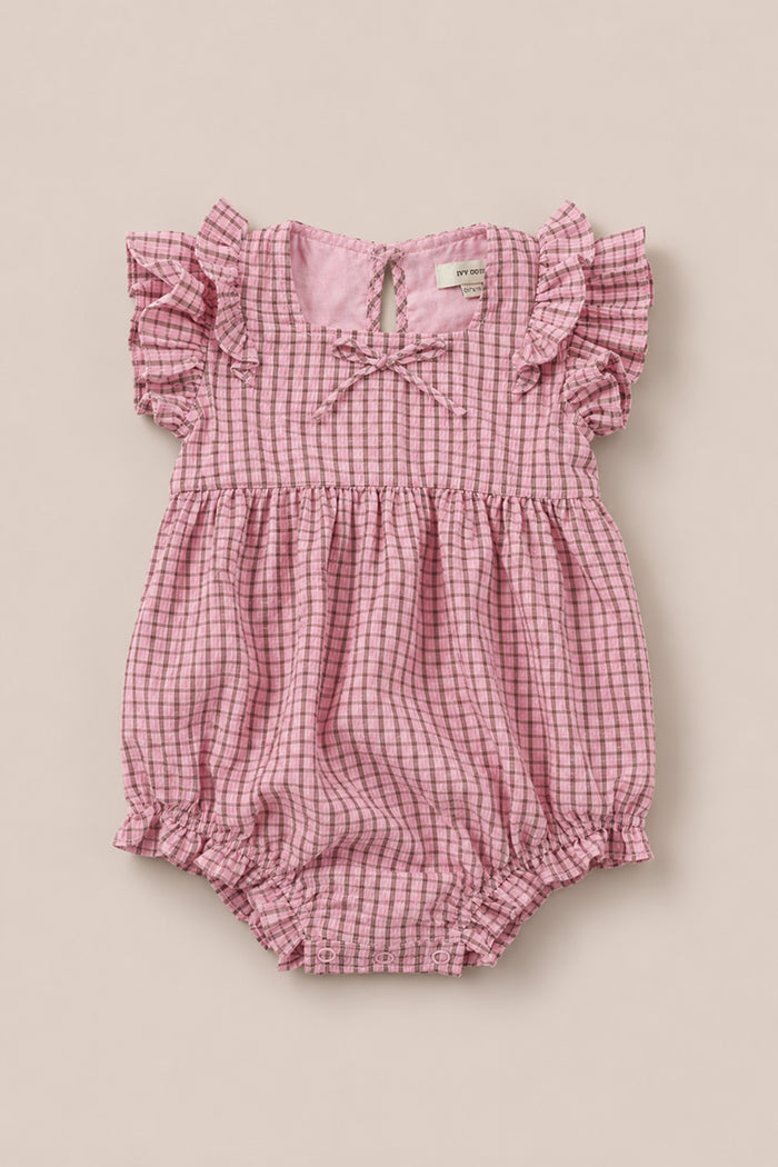Ivy City Co’s Baby Ana Romper in Pink & Brown Gingham features flutter sleeves, a gathered waist, elastic leg openings, and a small neckline bow, shown on a neutral background.