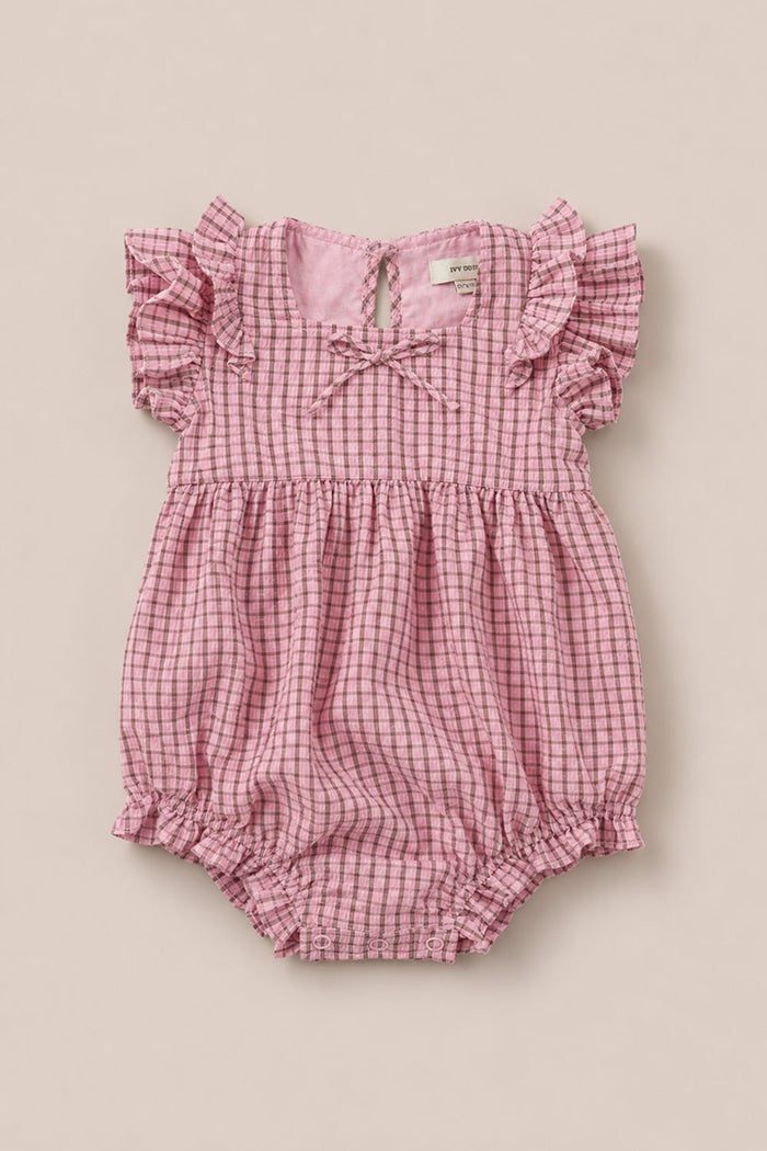 Dress your little one in the Baby Ana Romper in Pink & Brown Gingham from Ivy City Co. This adorable romper features short flutter sleeves, a sweet bow at the collar, and a charming pink and brown gingham pattern. Designed for comfort, it offers elastic leg openings and a gathered waist.