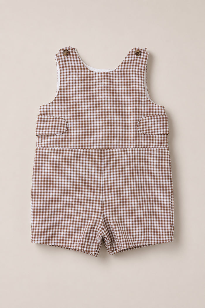 The Baby Boy Thomas Romper in Brown Gingham by Ivy City Co is a sleeveless, woven cotton romper with buttons on the shoulder straps and short legs, shown laid flat on a cream background.