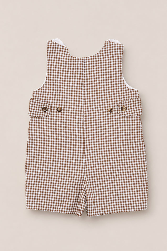The Ivy City Co Baby Boy Thomas Romper in Brown Gingham, featuring a sleeveless design, buttons at the waist, and short legs, is crafted from soft woven cotton fabric and displayed laid flat on a light beige background.