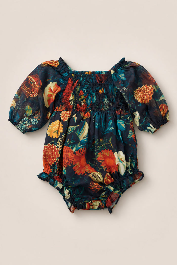 The Baby Madeline Romper in Imogen Moody Floral by Ivy City Co is beautifully displayed on a plain background, showcasing its short puff sleeves and dark floral print in rich red, orange, and green tones. An elegant chiffon finish and smocked bodice add extra charm to this delightful piece.