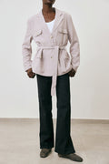 Person wearing a light pink blazer and black pants against a white background