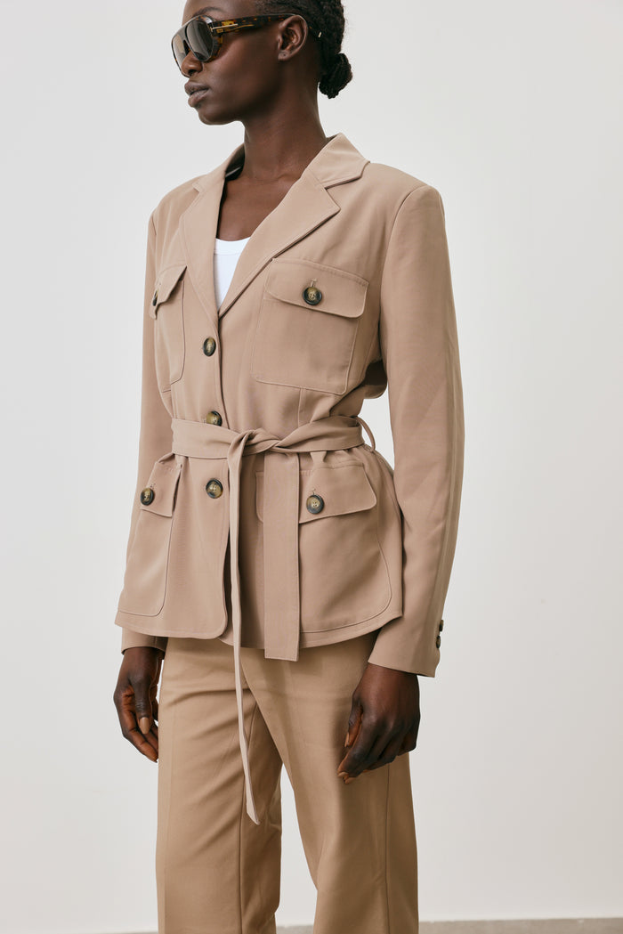 Person wearing a beige suit with a white background