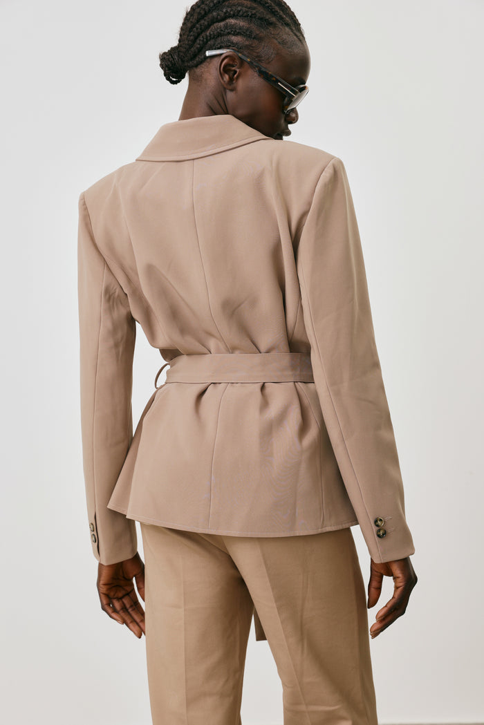 Person wearing a beige suit against a white background
