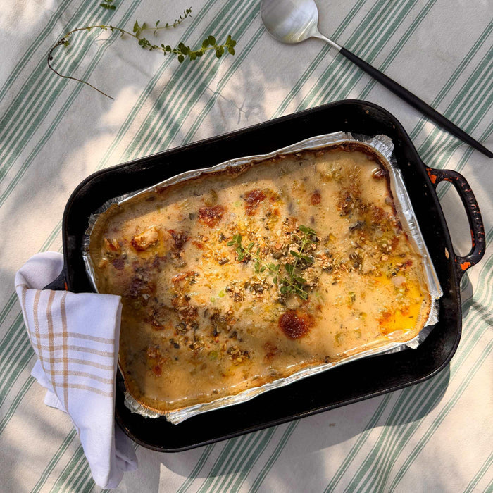 Pasture-raised organic casserole with herbs, served in a cast iron dish on a striped tablecloth