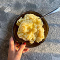 Creamy mashed potatoes in rustic bowl with butter, held over stone surface — organic, gluten-free ready meal