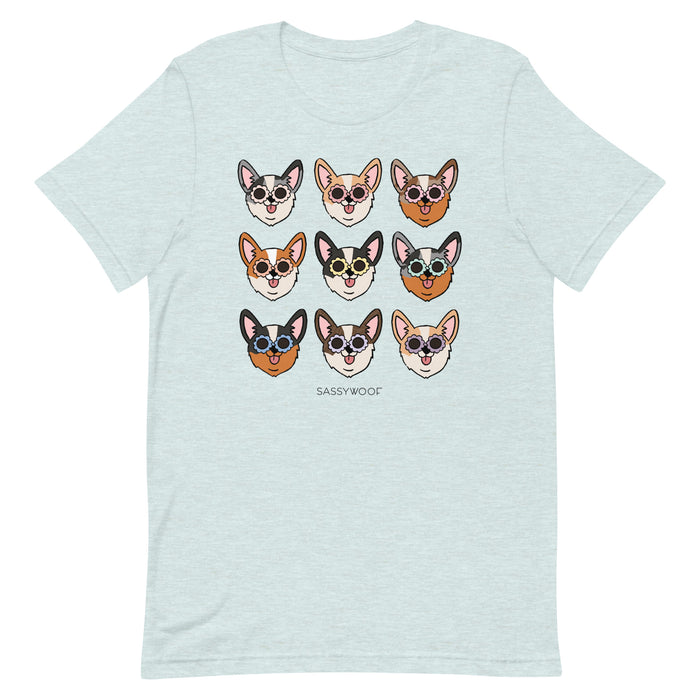 The Sassy Woof Corgi Tee is a light blue unisex t-shirt made from 100% cotton, showcasing nine illustrated corgi faces with sunglasses in a 3x3 grid above the “SASSY WOOF” logo. Each corgi has unique colors and playful expressions.