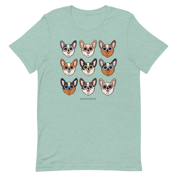 The Sassy Woof Corgi Tee is a light green, 100% cotton unisex shirt featuring nine illustrated corgi faces with sunglasses and "SASSY WOOF" printed below the design.