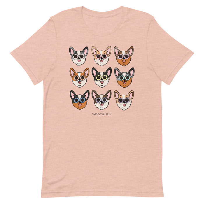 The Sassy Woof Corgi Tee is a light pink unisex 100% cotton shirt with nine cartoon corgi faces wearing sunglasses in a 3x3 grid and “SASSY WOOF” printed below the playful design.