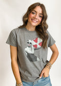 Woman wearing a gray t-shirt with a graphic design on a plain background
