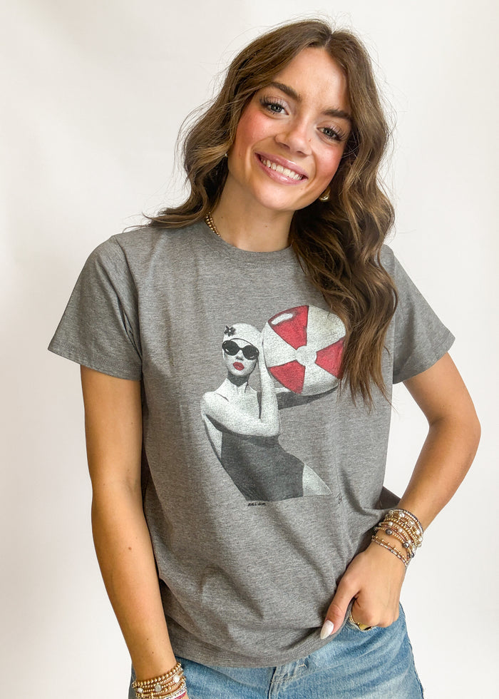 Woman wearing a gray t-shirt with a graphic design on a plain background