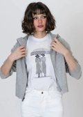 Woman wearing a black and white graphic tee with white jeans and a grey jacket