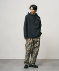 Model wearing bark camo Denim Gramicci Pant Straight Fit and a black hoodie on a light-tone background.