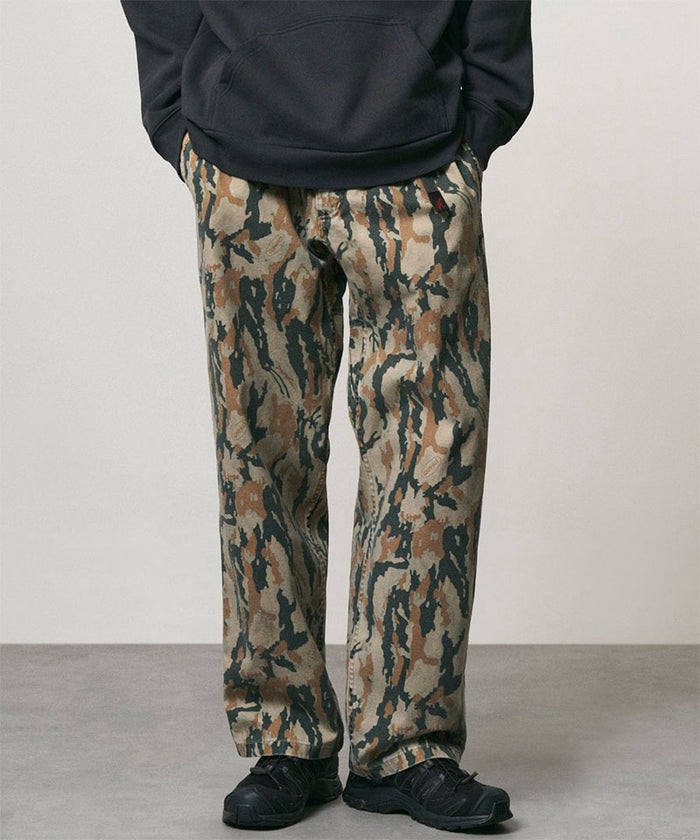 Model wearing bark camo Denim Gramicci Pant Straight Fit and a black hoodie on a light-tone background.