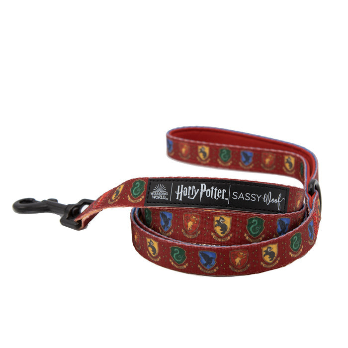 The Sassy Woof Dog Leash - Harry Potter™ is a red leash with Hogwarts house crests, a black clasp, and a black "Harry Potter | Sassy Woof" label—ideal for fans seeking magical pet accessories.