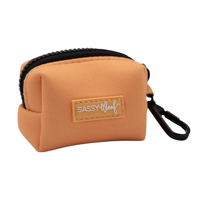 The Sassy Woof Dog Waste Bag Holder - Adventure Orange is a small, peach neoprene pouch with a black clip and stitched label, perfect for holding waste bags on your adventures.