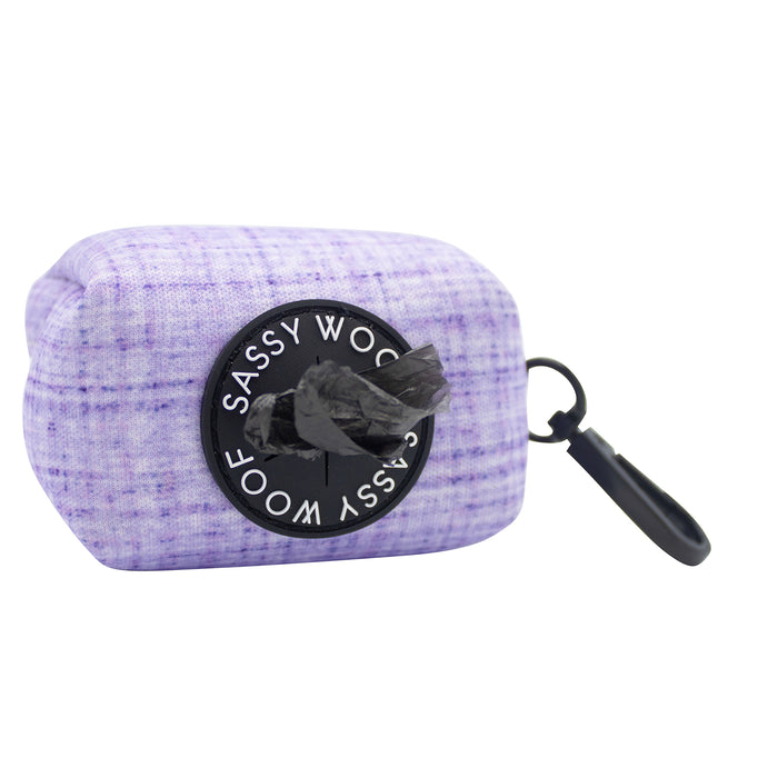 The Sassy Woof Dog Waste Bag Holder - Aurora is a purple neoprene holder with a black dispenser and clip, perfect for attaching to your leash or bag. A black waste bag is partially dispensed.