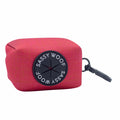 The Sassy Woof Dog Waste Bag Holder - Merlot is a red textured neoprene accessory featuring a black circular logo and a gray clip for easy carrying—perfect for daily walks with your pup.