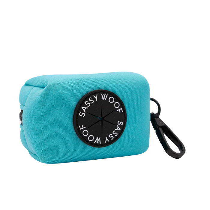 The Sassy Woof Dog Waste Bag Holder in Neon Blue is a rectangular neoprene pouch with a black circular Sassy Woof patch and clip—perfect for carrying small items or bags. Pair with matching harnesses or neon dog accessories.