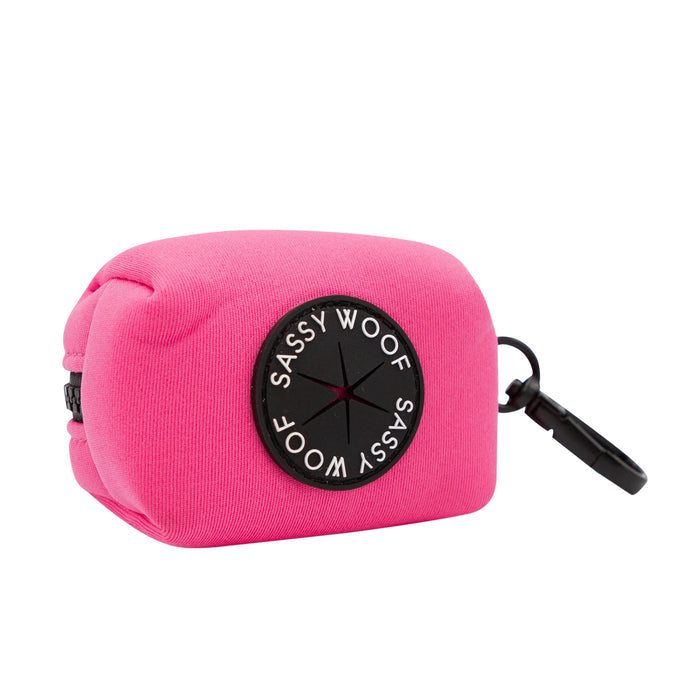 The Sassy Woof Dog Waste Bag Holder - Neon Pink features a black patch and a sturdy clip, perfect for carrying small items. Pair it with matching accessories for vibrant dog walks.