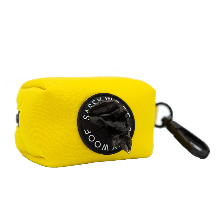 The Sassy Woof Dog Waste Bag Holder in Neon Yellow is a rectangular neoprene pouch with a black clip and easy-access circular opening—ideal to pair with your matching harness or other neon dog accessories.