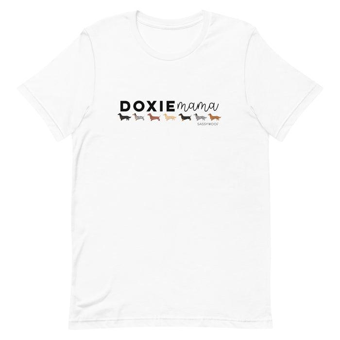 The Sassy Woof Doxie Mama Tee is a white unisex shirt featuring "DOXIE mama" above five colorful dachshunds and the brand name beneath. Perfect for any dog lover.