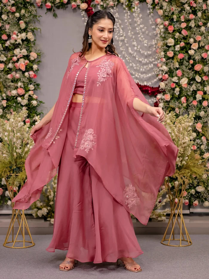 Woman in a pink saree with floral decorations in the background