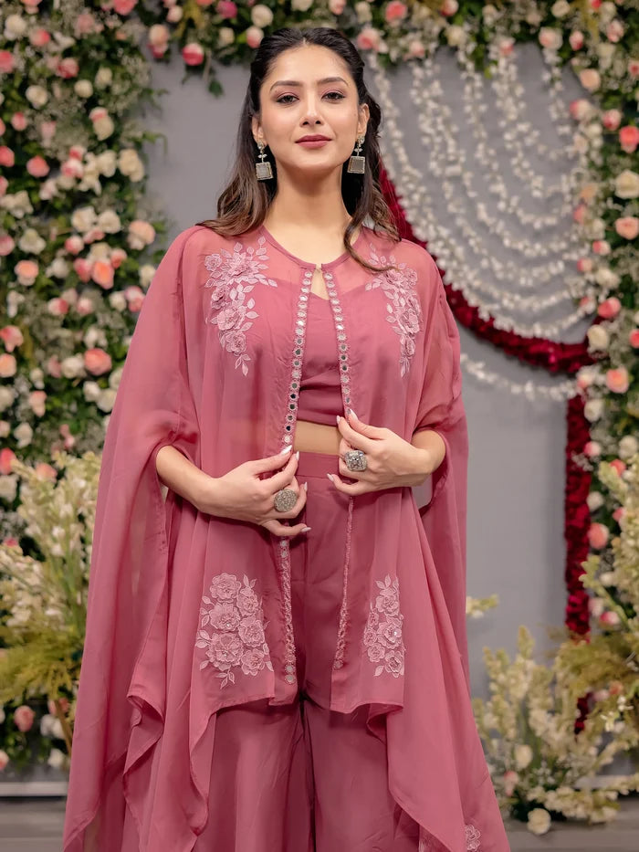 Woman in a pink traditional outfit standing in front of floral decorations