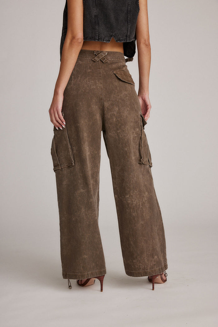 Back view of brown wide-leg cargo pants with flap pockets, styled with a denim vest.