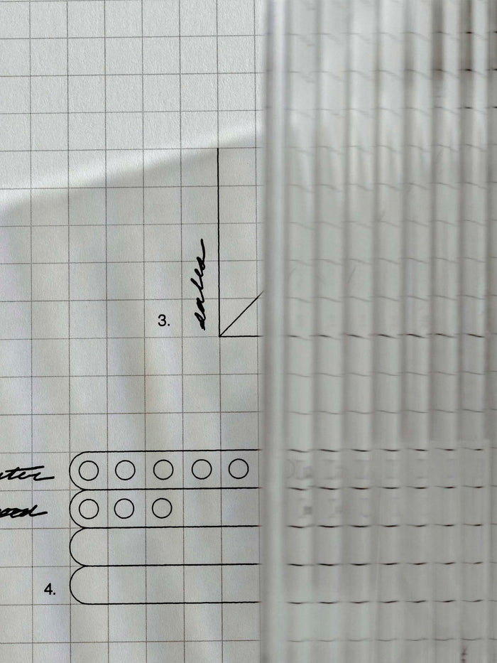 Photo focusing on the texture and light reflections caused by the dashboard on a piece of graph paper.