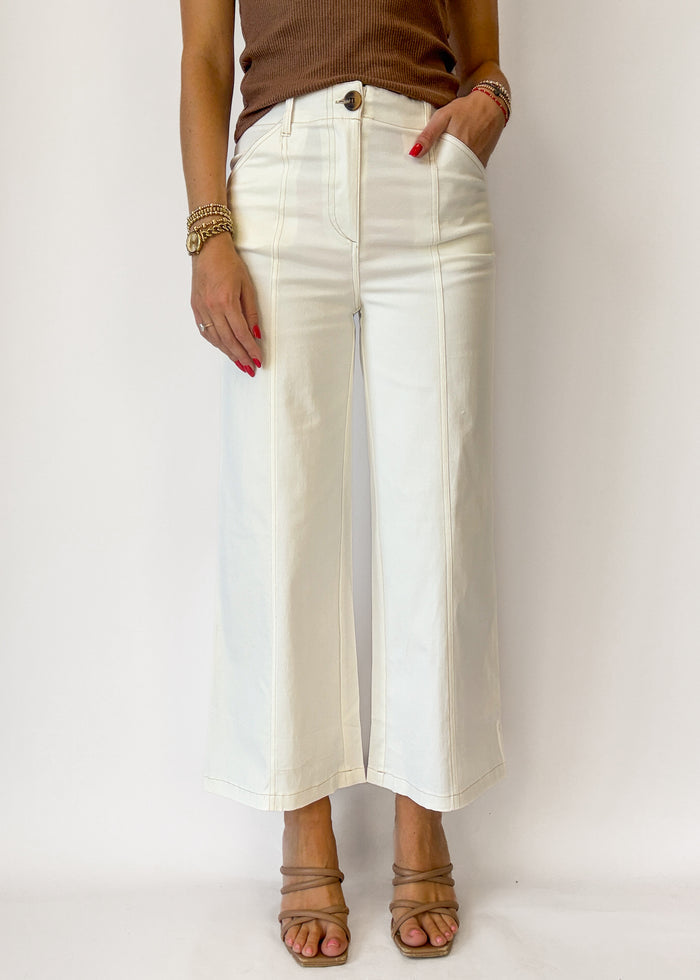 Person wearing white pants and a brown top on a plain background
