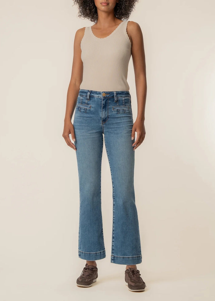 Person wearing blue jeans and a beige top on a plain background