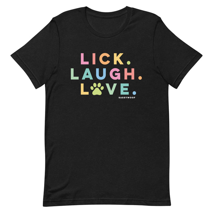 The Lick, Laugh, Love Tee by Sassy Woof is a lightweight black summer shirt with "LICK. LAUGH. LOVE." in bold colors featuring a yellow paw print O—perfect as a unisex pet shirt for dog lovers. "Sassy Woof" appears subtly below in white.