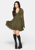 Woman wearing an olive green dress with long sleeves and black knee-high boots on a white background