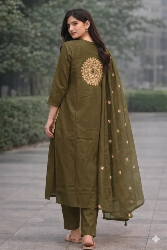 A woman wearing an olive green traditional outfit with gold embroidery in an outdoor setting.