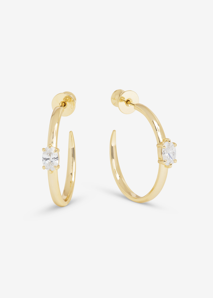 Gold hoop earrings with a diamond stud sitting on a white background