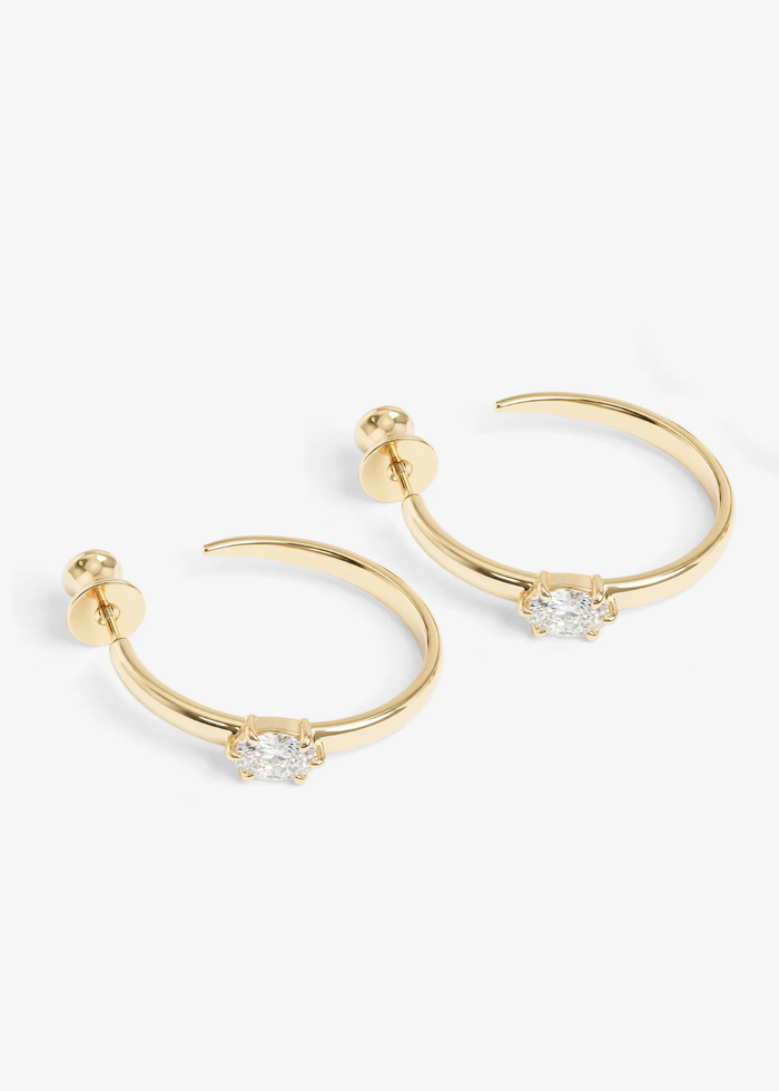Gold hoop earrings with a diamond stud laying on a white background