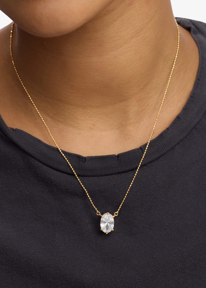 Woman wearing a gold simulated diamond pendant necklace