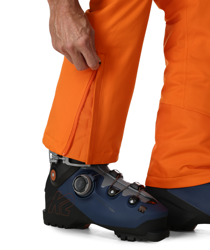 Person wearing orange ski pants with blue ski boots on a white background