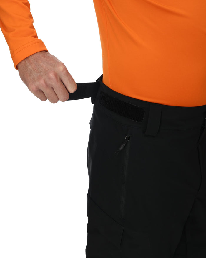 Person wearing black pants with an orange shirt on a white background