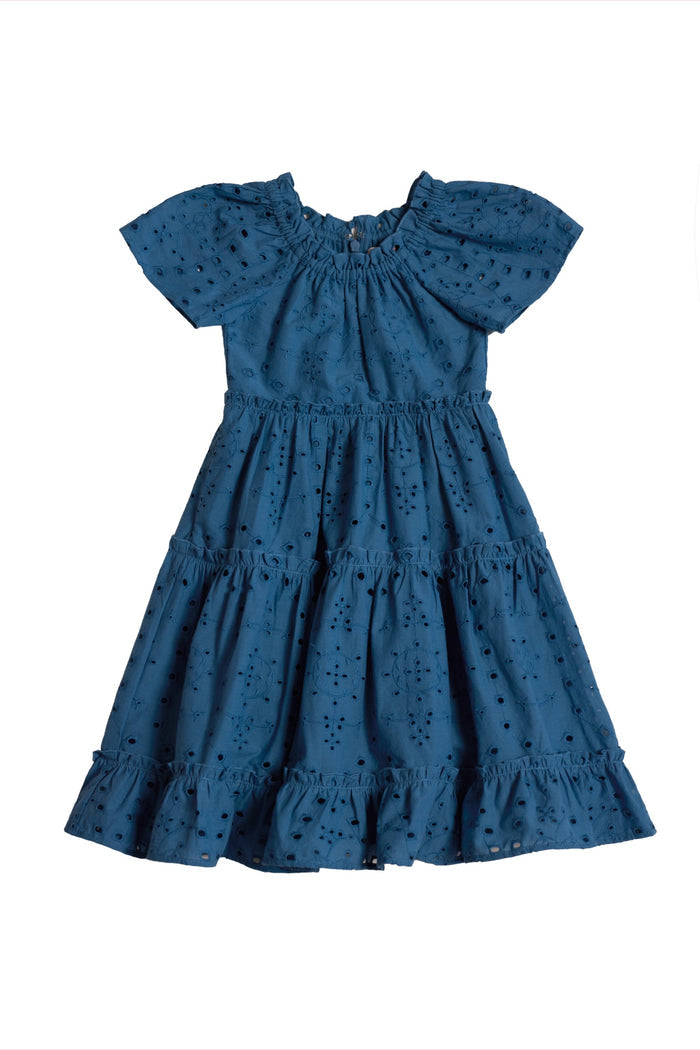 The Ivy City Co Mini Etta Dress in Cobalt is a blue, short-sleeved girls’ cotton dress with a ruffled hem, tiered skirt, embroidered eyelet pattern, and gathered neckline for elegant texture. Shown laid flat on a white background.