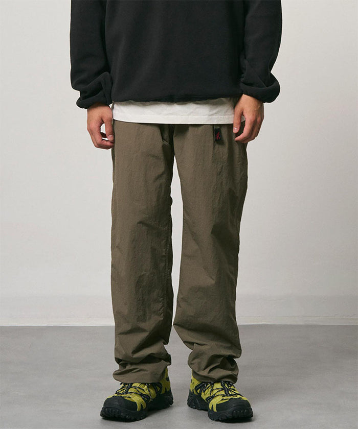 Burnt olive colored Nylon Gramicci Pants with a belt against a light-tone background.