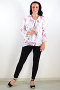 Pink floral botanical tunic top by Caroline Morgan, featuring a flowy fabric and vibrant botanical print, displayed on a hanger.