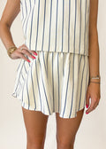 Person wearing a white and navy striped outfit on a plain background