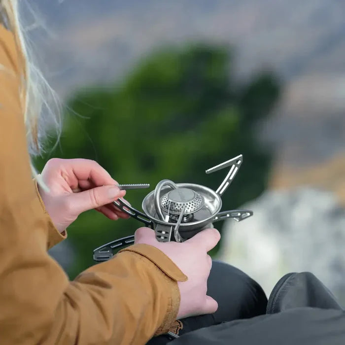 Person holding a Primus Easy Fuel Camping Gas Stove with a blurred natural background