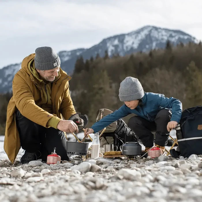 Man and child preparing food on a Primus Easy Fuel Camping Gas Stove in a mountainous area