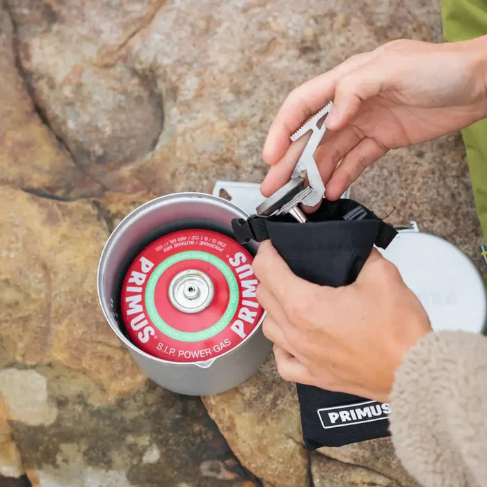 Person setting-up a Primus Express Camping Gas Stove Piezo Ignition on a rocky surface