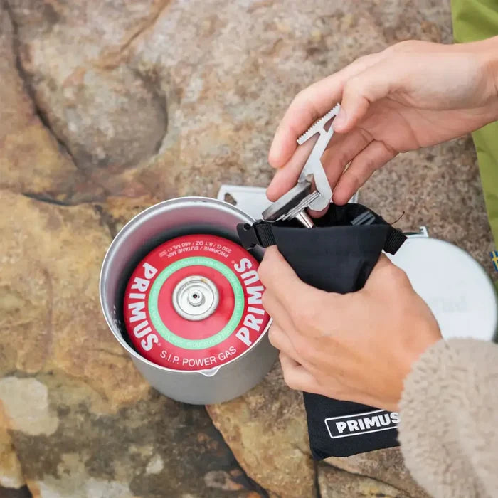 Lifestyle image of a person packing away a Primus Express camping gas stove in to its carry case.