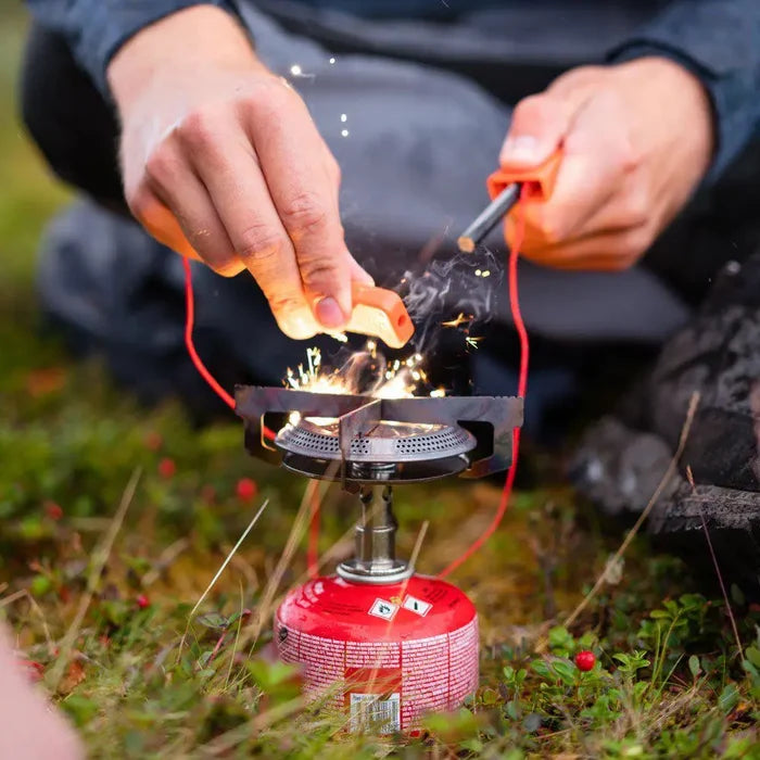Person igniting a Primus Mimer Camping Gas Stove with a flint lighter outdoors