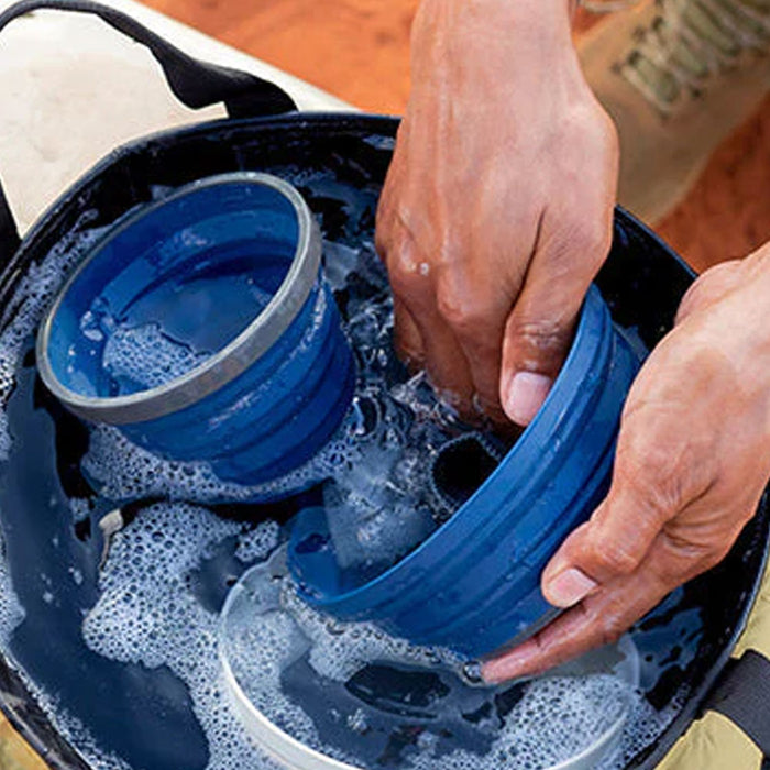 Lifestyle image of a person washing up their camping dinnerware in a Sea To Summit portable kitchen sink